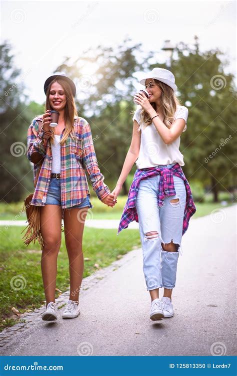 2 women holding hands|two girls walking holding hands.